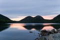 Pond with reeds and rocks and forested hills in the background Royalty Free Stock Photo