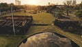 Pond with sun reflection at designed green park aerial. Green grass valey with lake at path Royalty Free Stock Photo