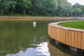 Pond with water and a floating white night lamp. In the background a park with green trees. Royalty Free Stock Photo