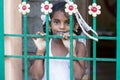 Closeup portrait of shy timid young pretty Indian girl child looking away and behind gate. Freedom concept. Royalty Free Stock Photo