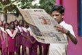 Documentary editorial image. Young man with uniform reads newspaper in the school