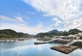 Pontoon pier on turquoise water in the Kujukushima Pearl Sea Resort surrounded by mountains.