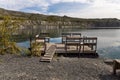 Pontoon with a wooden table and benches for relaxation is on the blue water of the lake Royalty Free Stock Photo