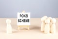 PONZI SCHEME text on a easel with wooden figure, meeting concept