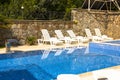 Pool with blue water ladder for descent and ascent into the water. The sun loungers are empty by the pool