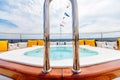 Pool on the board of a ship surrounded by colorful pillows