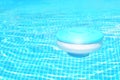 Pool cleaning chemicals background. Floating chlorine tablet dispenser for pools lies in water
