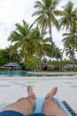 Pool with a first-person view. One can see the male legs on a deck chair Royalty Free Stock Photo