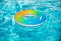 Pool float, rainbow ring floating in a refreshing blue swimming pool. Inflatable ring floating in pool on summer Royalty Free Stock Photo