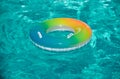 Pool float, rainbow ring floating in a refreshing blue swimming pool. Inflatable ring floating in pool on summer Royalty Free Stock Photo