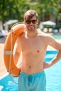 Handsome young man in sunglasses standing near swimming pool Royalty Free Stock Photo