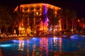 Pool and hotel in the evening. People relax by evening near pool. Lights of evening hotel are reflected in pool water in night Royalty Free Stock Photo