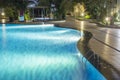 Pool at night with lush greenery and lighting for home design and landscaping in the backyard. Night shadows and reflections on t