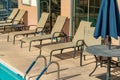 Pool side lounging chairs for sunbathing and recreation near pool with visible tables and umbrellas during the summer Royalty Free Stock Photo