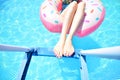 Pool time. Female legs holding ladder in a swimming pool Royalty Free Stock Photo