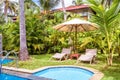 Pool with umbrella and beach beds in tropical hotel or residential house Royalty Free Stock Photo