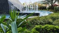 pool, waters gushing from the fountain. green garden and buildings.