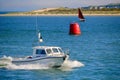 Poole, Dorset, England - June 02 2018: White motor boat speeds through the blue ocean past a marker buoy with a 10 knot speed limi Royalty Free Stock Photo