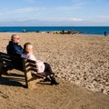 Couple Sitting On A Wooden Bench Relaxing Looking Out To Sea Royalty Free Stock Photo