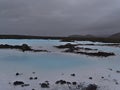 Pools with blue thermal water and white deposits surrounded by lava fields and volcanic rocks near Blue Lagoon, Iceland.