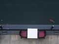 Poolside small white coffee table with red brown chairs for two view from above with large swimming colourful Japanese koi fish in Royalty Free Stock Photo