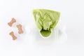 Poop bags with dog treats on white background