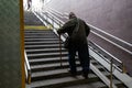 poor adult man leans on a cane and climbs the stairs from the underpass Royalty Free Stock Photo