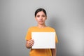 Poor asian young woman in yellow shirt protests against a grey background