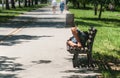 Poor barefoot homeless man or refugee sleeping on the wooden bench on the urban street in the city, social documentary concept, se