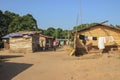Poor, but clean typical African Ugandan village with wooden houses, a local resident walks along the street, clothes are dried on