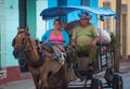 Poor Cuban couple in traditional colorful alley with traditional carriage, in old Trinidad, Cuba, America.