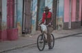 Poor Cuban old man in traditional colorful alley with old colonial house and bicycle, in old town, Cuba, America.