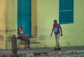 Poor Cuban old people capture portrait in traditional colorful alley with old colonial house, in old town, Cuba, America.