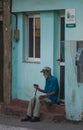 Poor Cuban old people in traditional colorful alley with old colonial house, in old town, Cuba, America.