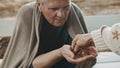 Poor elder homeless man receiving coins from woman Royalty Free Stock Photo