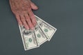 Poor elderly woman is counting some American Dollars in her hand. wrinkled Hands of an old woman on a gray background. Counting Royalty Free Stock Photo