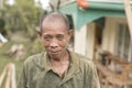 A poor Filipino man in his late 50s and early 60s wearing an old faded green collared shirt. A villager posing outdoors