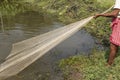 A poor fisherman in a village in West Bengal, India, is fishing with nets from the pond