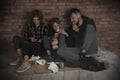 Poor homeless family sitting on floor near wall Royalty Free Stock Photo