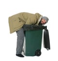 Poor homeless man digging in trash bin isolated