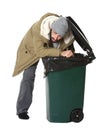 Poor homeless man digging in trash bin on white