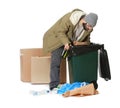 Poor homeless man digging in trash bin on white