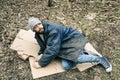 Poor homeless man lying on ground in park