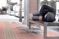 Poor homeless man or refugee sleeping on the wooden bench on the Sidewalk in the city Royalty Free Stock Photo