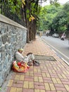 A poor and homeless man siting on the pavement besides a road Royalty Free Stock Photo