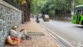 A poor and homeless man siting on the pavement besides a road Royalty Free Stock Photo