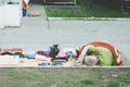 Poor homeless street vendor sleeps on the ground covered with blanket.