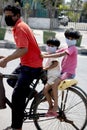 Poor Indian with two children`s riding in a bicycle wearing mask . Covid- 19 .