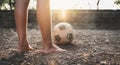 Poor kid playing old soccer or football on ground with glowing sunlight background and hope concept