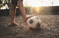 Poor kid playing old soccer or football on ground with glowing sunlight background and hope concept Royalty Free Stock Photo